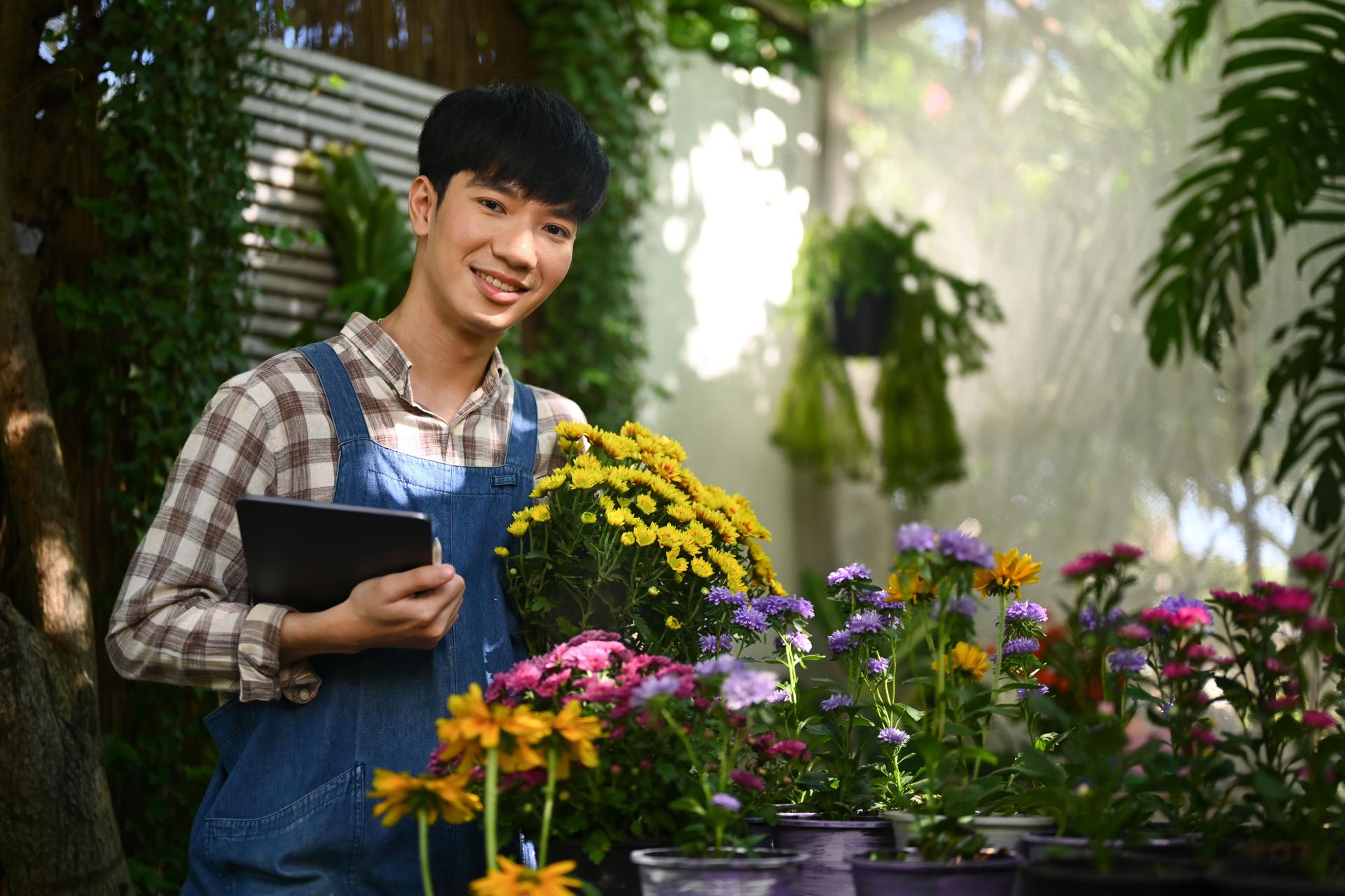 Handsome Asian male florist holding fresh flowers working in his floral shop