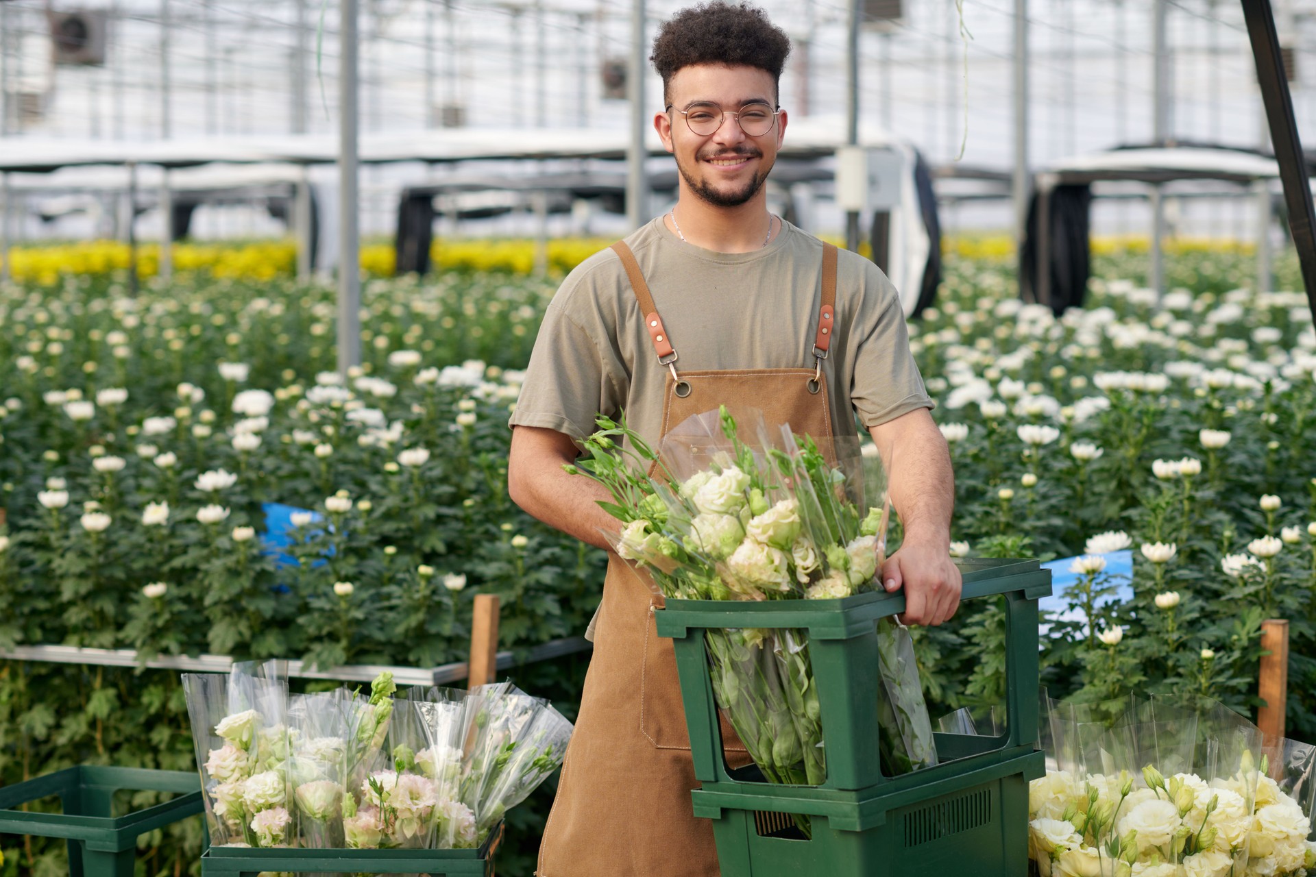 Young successful gardener or clerk of flowers holding box with fresh eustomas