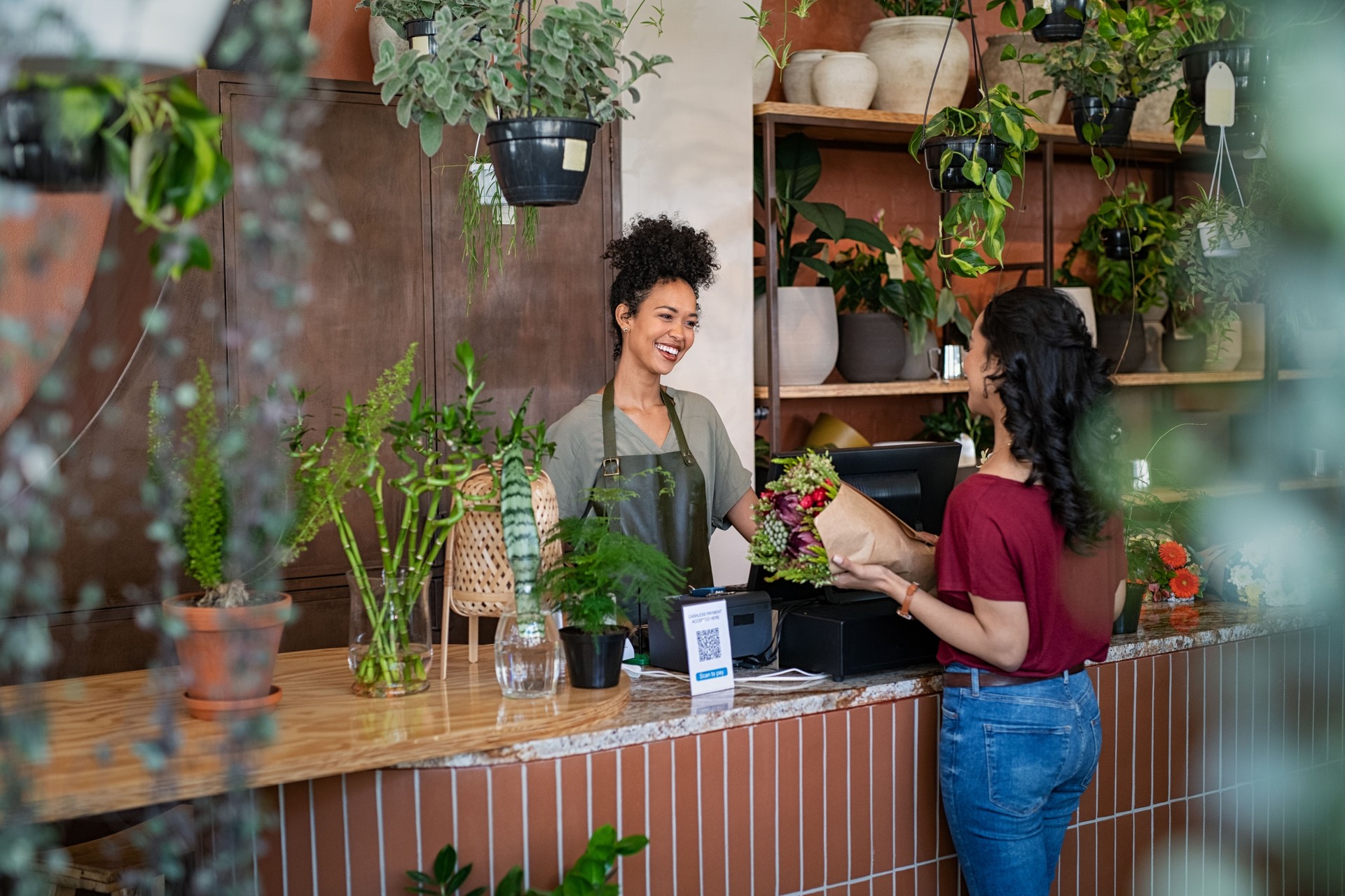 Happy florist selling plants and flower to client